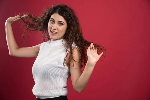 Güzel Bir Kadın Kırmızı Arka Planda Kıvırcık Siyah Saçlarına Dokunuyor — Stok fotoğraf