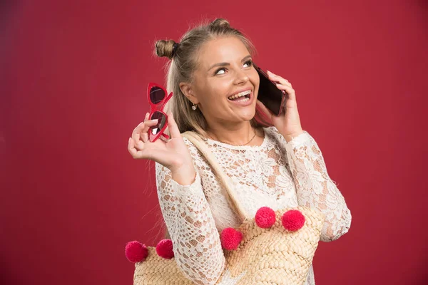 Leende Kvinna Talar Telefon Med Väska Och Glasögon Röd Bakgrund — Stockfoto