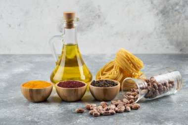 Gri arka planda çiğ fasulye ve çiğ makarnayla dolu cam bir kavanoz. Yüksek kalite fotoğraf