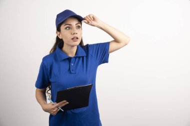Beyaz arka planda panosu olan mavi üniformalı bir teslimatçı kadın. Yüksek kalite fotoğraf