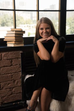 Gülümseyen kadın pencerenin yanında kitaplarla poz veriyor.