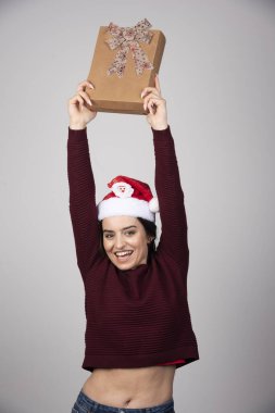 Gri arka planda duran Noel hediyeli genç bir kadın. Yüksek kalite fotoğraf