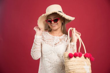 Kırmızı arka planda şapkalı ve gözlüklü gülen kadın. Yüksek kalite fotoğraf