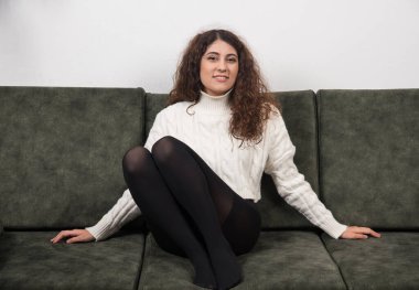 Kanepede oturan ve kameraya bakan gülümseyen bir kadın. Yüksek kalite fotoğraf