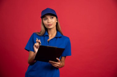 Mavi üniformalı genç bir kadın elinde not panosu ve kalemle poz veriyor. Yüksek kalite fotoğraf