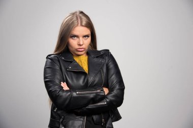Siyah deri ceketli sarışın kız profesyonel ve sıkı bir duruş sergiliyor. Yüksek kalite fotoğraf