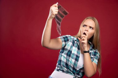 Genç sarışın model polaroid film sahnelerini kontrol ediyor ve tatmin olmamış ve korkmuş görünüyor. Yüksek kalite fotoğraf