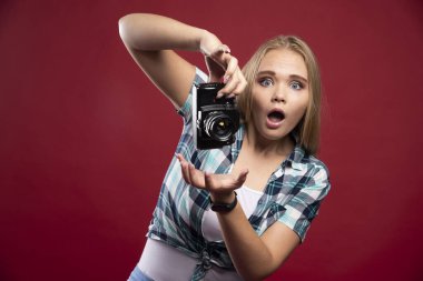 Profesyonel bir kamera tutan genç sarışın fotoğraf ve tuhaf pozisyonlarda selfie çekiyor. Yüksek kalite fotoğraf