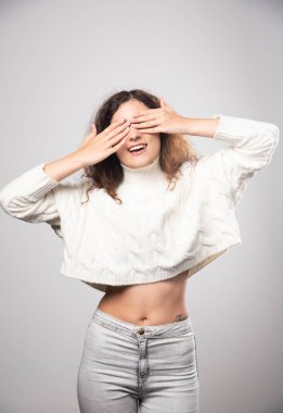 Beyaz kazaklı genç bir kadın gözlerini kapatıyor. Yüksek kalite fotoğraf