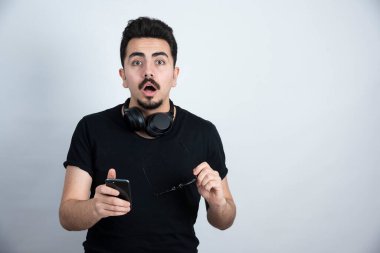 Esmer adam, kulaklık takıyor ve cep telefonu tutuyor. Yüksek kalite fotoğraf