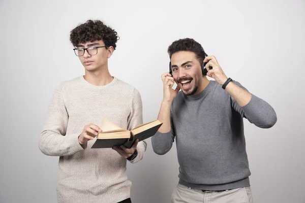 两个年轻人拿着一本书 戴着耳机 高质量的照片 — 图库照片
