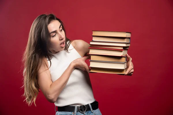 Die Junge Studentin Hält Einen Stapel Bücher Auf Rotem Hintergrund — Stockfoto