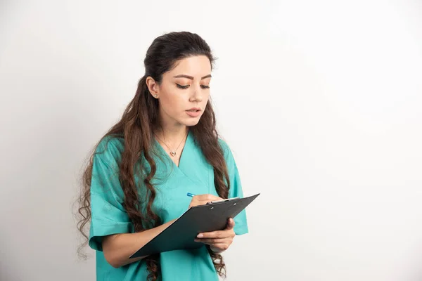 白い背景にクリップボードに書かれた女性医療従事者の肖像画 高品質の写真 — ストック写真