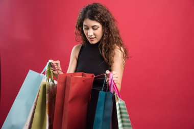 Kırmızı arka planda çantaya bakan bir kadın. Yüksek kalite fotoğraf