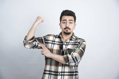 Beyaz duvarın üzerinde kaslarını gösteren gözlüklü sakallı bir adam portresi. Yüksek kalite fotoğraf