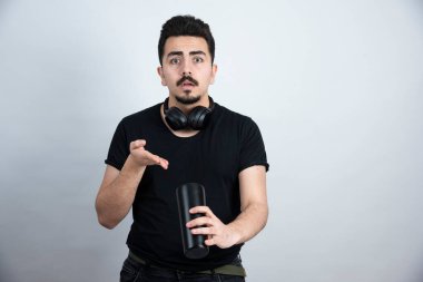 Esmer adam bir kupa tutuyor ve kameraya bakıyor. Yüksek kalite fotoğraf