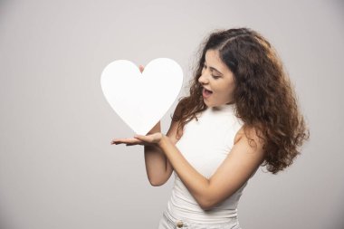 Beyaz el yapımı kağıt kalbe bakan genç bir kadın. Yüksek kalite fotoğraf