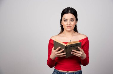 Elinde açık bir kitapla kameraya bakan genç bir kadın. Yüksek kalite fotoğraf