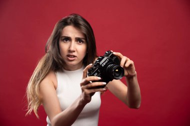 Kırmızı arka planda kamerayla poz veren güzel bir kadın. Yüksek kalite fotoğraf