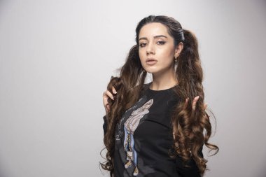 Saçlarını gri arka planda tutan genç ve güzel bir kadın. Yüksek kalite fotoğraf