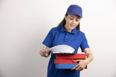 Kadın kurye, karton pizza ve panoya bakıyor. 