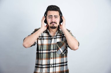 Beyaz arka planda ağlayan kulaklıklı yakışıklı bir adam resmi. Yüksek kalite fotoğraf