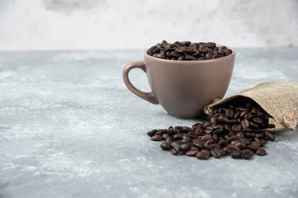 Geröstete Kaffeebohnen Aus Einem Kleckssack Und Einer Tasse Auf Marmorgrund — Stockfoto