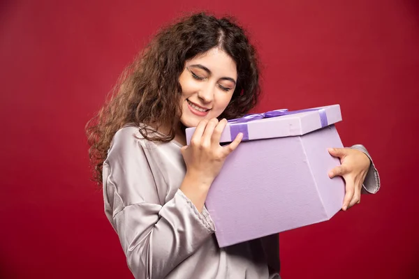 Mujer Joven Sosteniendo Caja Regalo Púrpura Sobre Fondo Rojo Foto —  Fotos de Stock