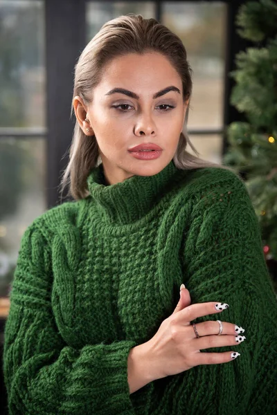 真剣な女性はクリスマスツリーの近くにポーズを暖かいセーターを着て 高品質の写真 — ストック写真