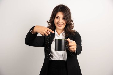 Bayan ofis çalışanı bir fincan çay ikram ediyor ve onu işaret ediyor. Yüksek kalite fotoğraf