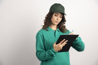 Yeşil üniformalı teslimatçı kadın sipariş detaylarını yazıyor. Yüksek kalite fotoğraf