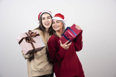 Noel Baba şapkalı iki gülümseyen kız Noel hediyesi taşıyor. Yüksek kalite fotoğraf