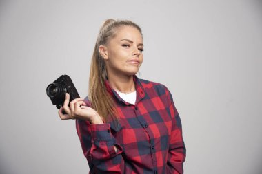 Kareli gömlekli sarışın manken fotoğraf çekerken pozitif ve alımlı görünüyor. Yüksek kalite fotoğraf