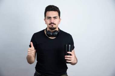 Esmer adam bir kupa tutuyor ve baş parmağını kaldırıyor. Yüksek kalite fotoğraf