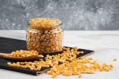 Siyah kesme tahtasının üzerinde kaşık olan cam mısır taneleri kavanozu. Yüksek kalite fotoğraf