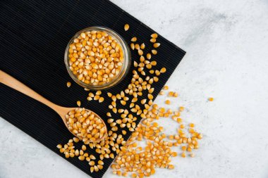 Cam kavanoz dolusu çiğ mısır taneleri ve siyah kesme tahtasının üzerinde kaşık. Yüksek kalite fotoğraf