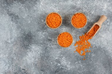 Ahşap kaplar dolusu kırmızı çiğ mercimek mermer arka planda. Yüksek kalite fotoğraf