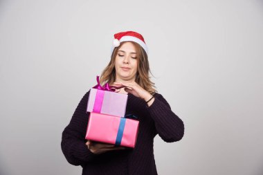 Noel Baba şapkalı genç bir kadın hediye kutularını tutuyor. Yüksek kalite fotoğraf