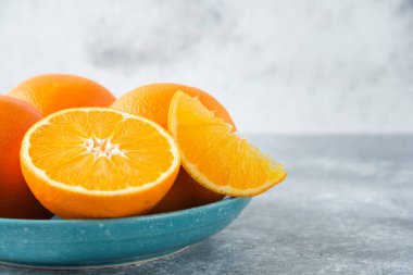 Taş zeminde dilimlenmiş ve sulu portakal meyveleriyle dolu bir tabak. Yüksek kalite fotoğraf