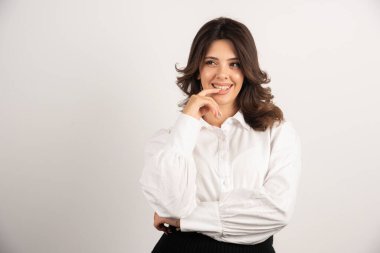 Genç bir çalışan beyaz arka planda parmağını ısırıyor. Yüksek kalite fotoğraf