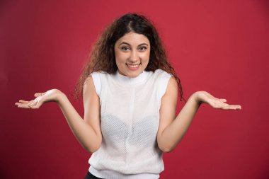 Gülümseyen kadın ellerini kırmızı arka planda gösteriyor.