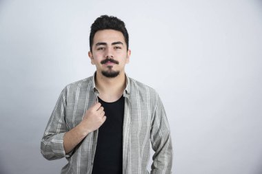 Beyaz duvarın üzerinde sıradan giyinmiş genç bir adamın fotoğrafı. Yüksek kalite fotoğraf