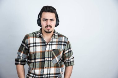 Kulaklıklı yakışıklı bir adamın beyaz duvardan kızgın bakışları. Yüksek kalite fotoğraf