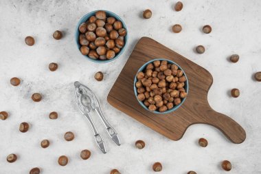 Mermer zemin üzerinde iki mavi kabuklu fındık ve çekirdek kasesi. Yüksek kalite fotoğraf