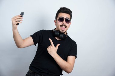 Esmer adam, kulaklık takıyor ve cep telefonu tutuyor. Yüksek kalite fotoğraf