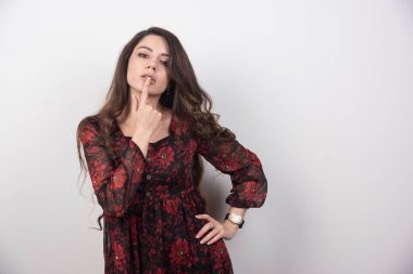 Ağzına baştan çıkarıcı bir şekilde dokunan uzun saçlı kadının portresi. Yüksek kalite fotoğraf