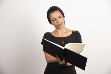 İş kadını beyaz arka planda defterine bakıyor. Yüksek kalite fotoğraf