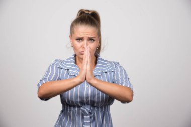 Gri arka planda birini selamlayan bir kadının portresi. Yüksek kalite fotoğraf