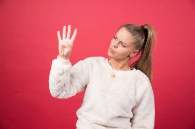 Kırmızı arka planda dört kişi sayan genç bir kız. Yüksek kalite fotoğraf