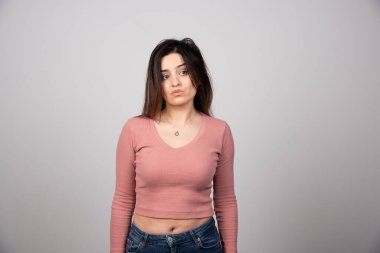 Üzgün genç bir kadın ayakta dikiliyor ve başka tarafa bakıyor. Yüksek kalite fotoğraf